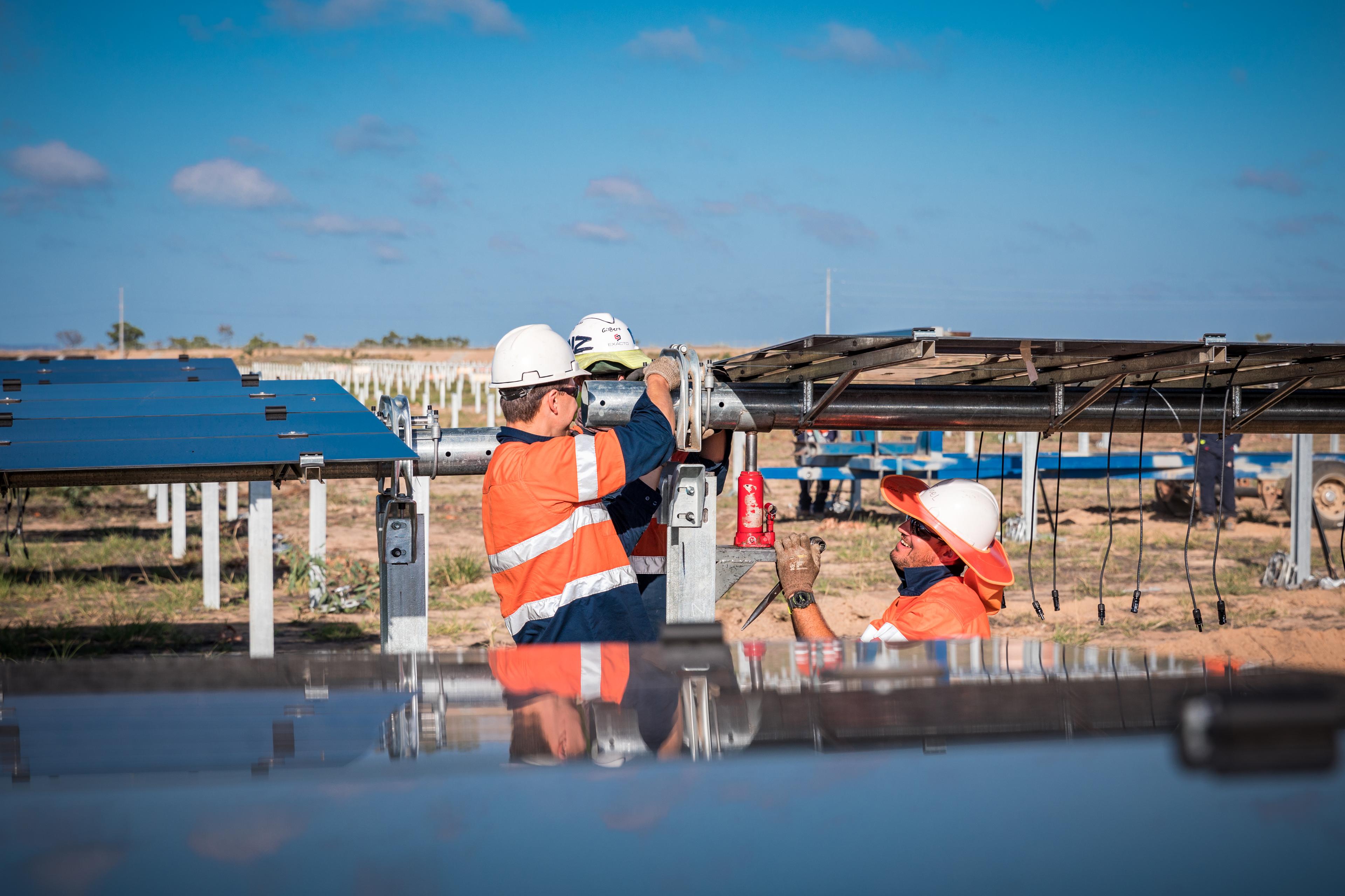 3 males in high-vis working on a solar panel farm